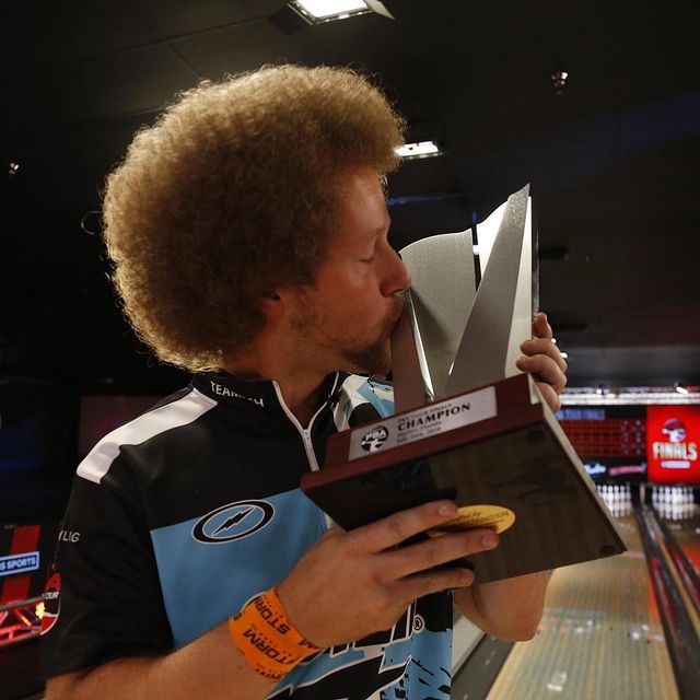Kyle Troup kissing his trophy in his bowling jersey.